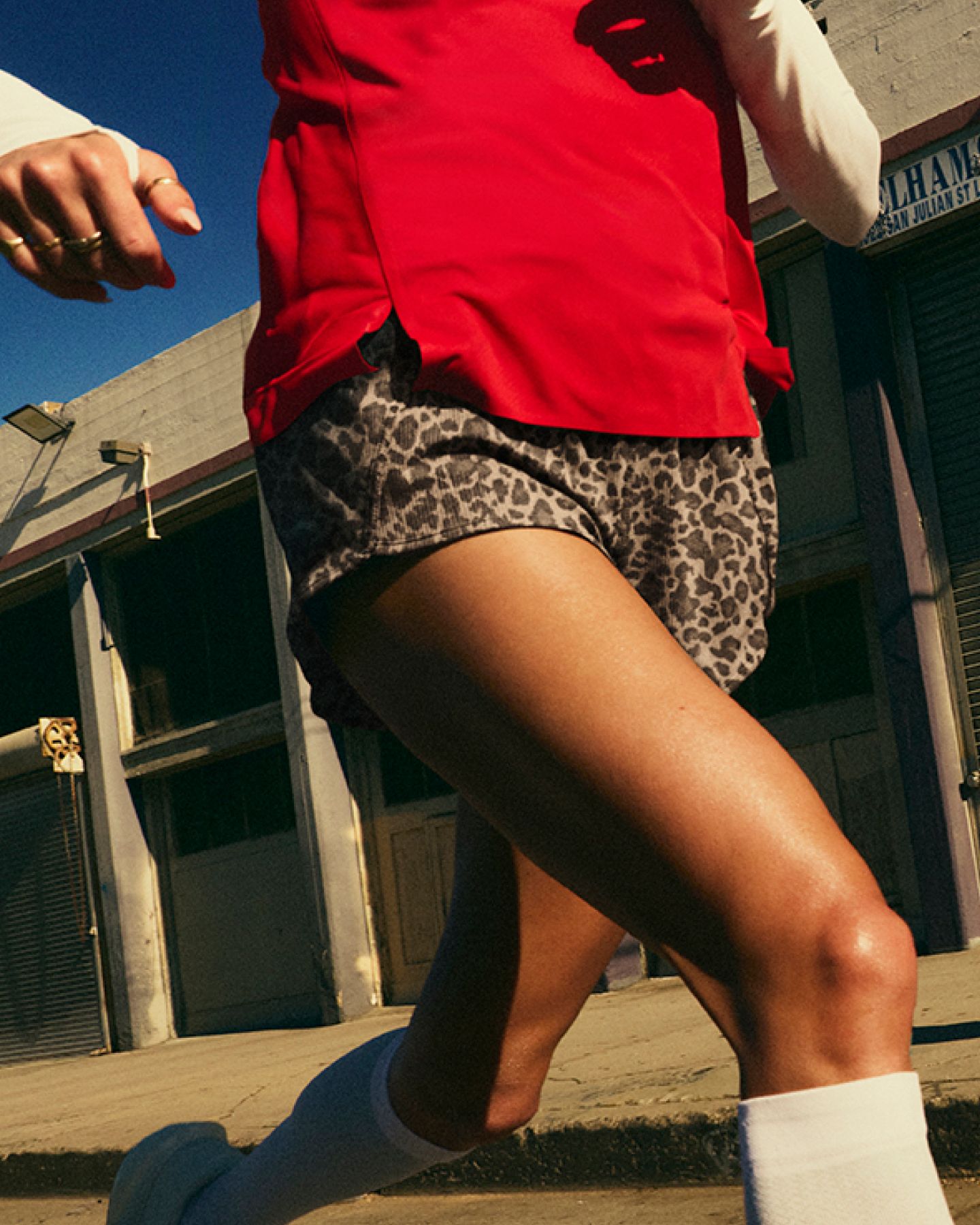 Close-up of a runner’s stride wearing red lululemon shorts on a city street.