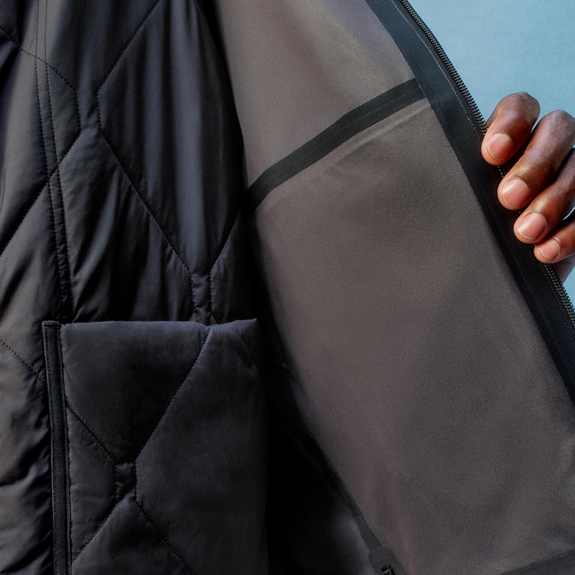 A close-up of a person wearing the Stretch Glyde Waterproof Jacket with their hand open it up to show the inner layer.