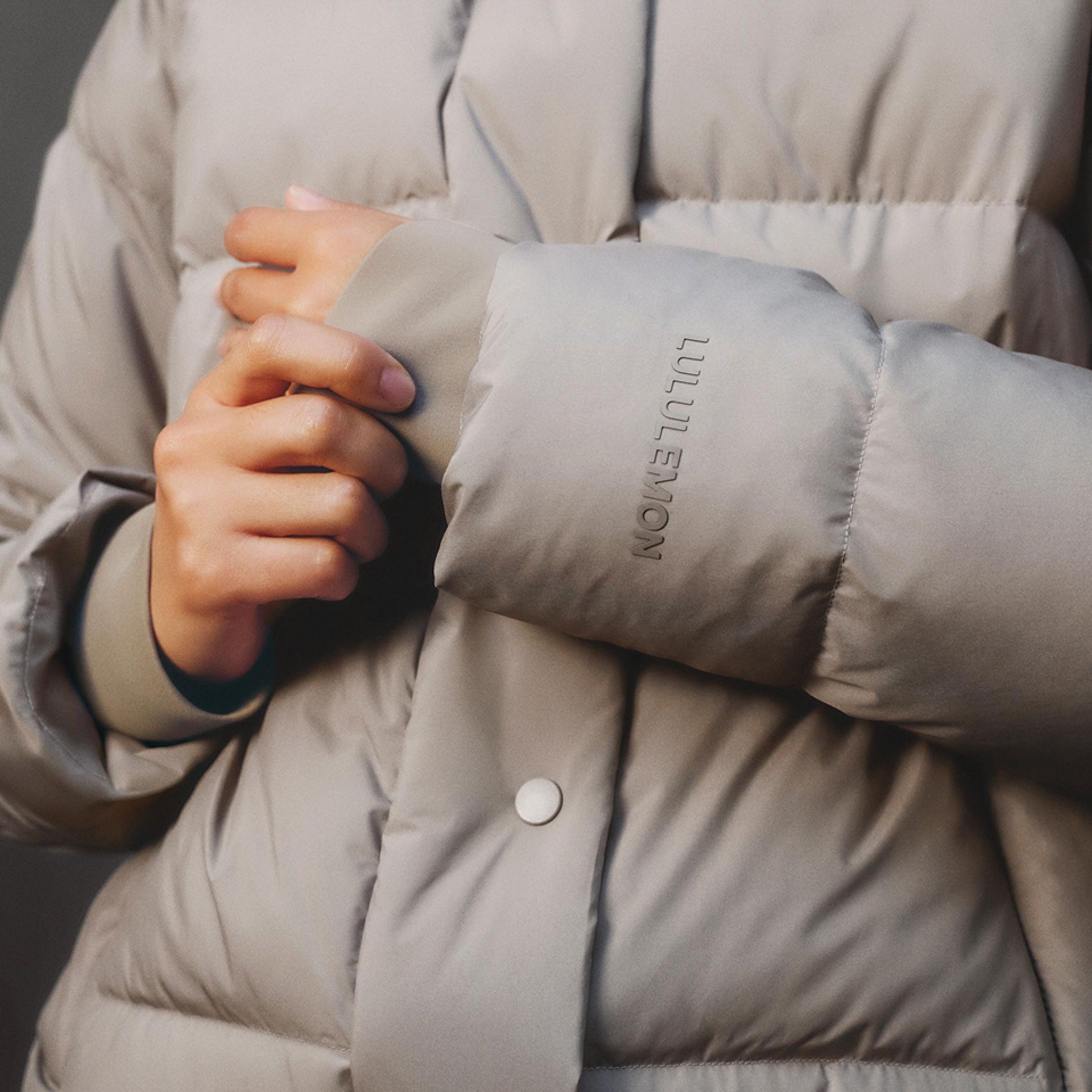 A close-up of a person wearing the Wunder Puff Jacket with one hand gripping the cuff.