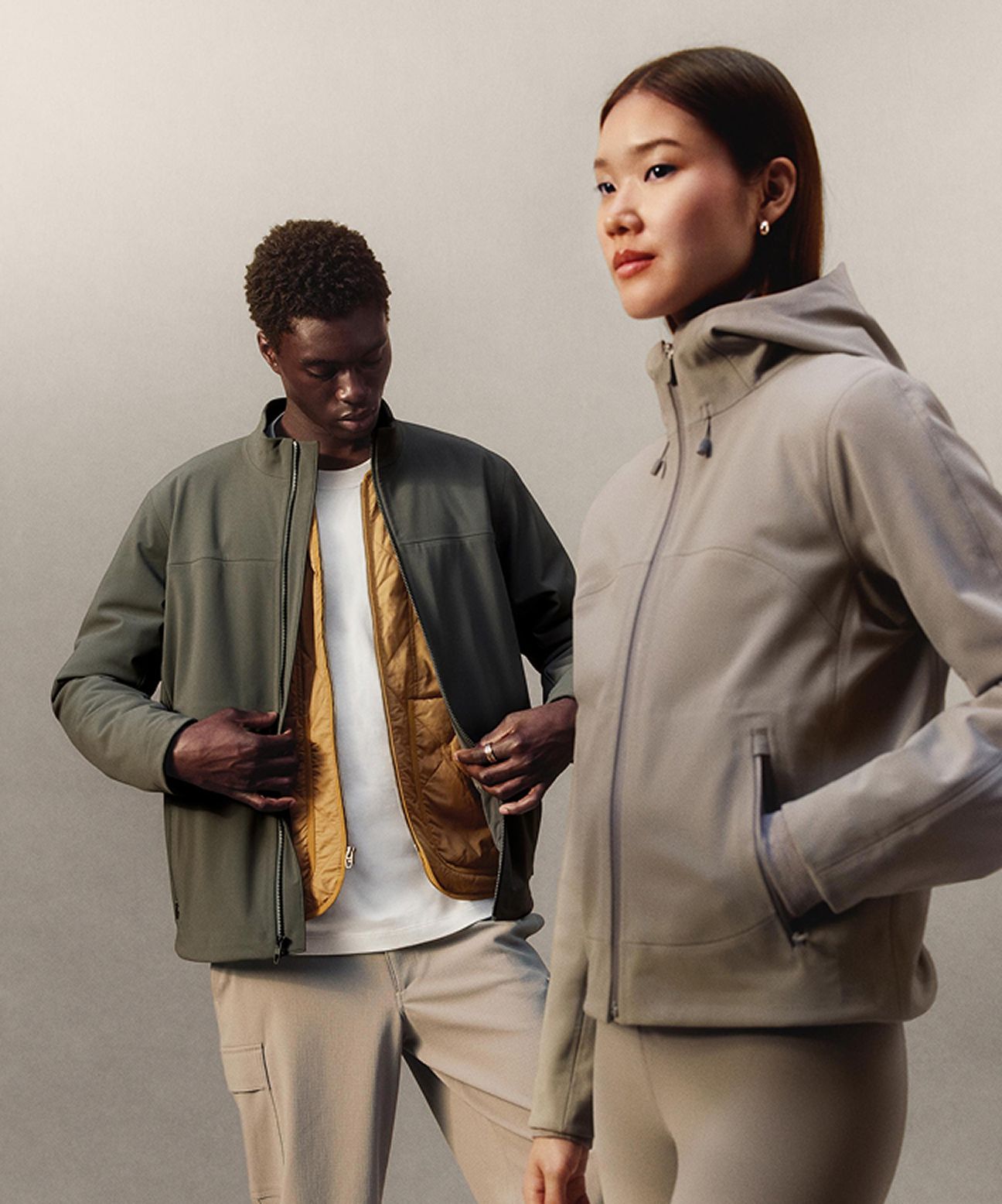 Two people standing modelling lululemon outerwear: one is wearing the Cross Chill Casual Jacket with the Diamond-Quilted Liner Jacket underneath, and the other is wearing the Cross Chill City-to-Trail Jacket