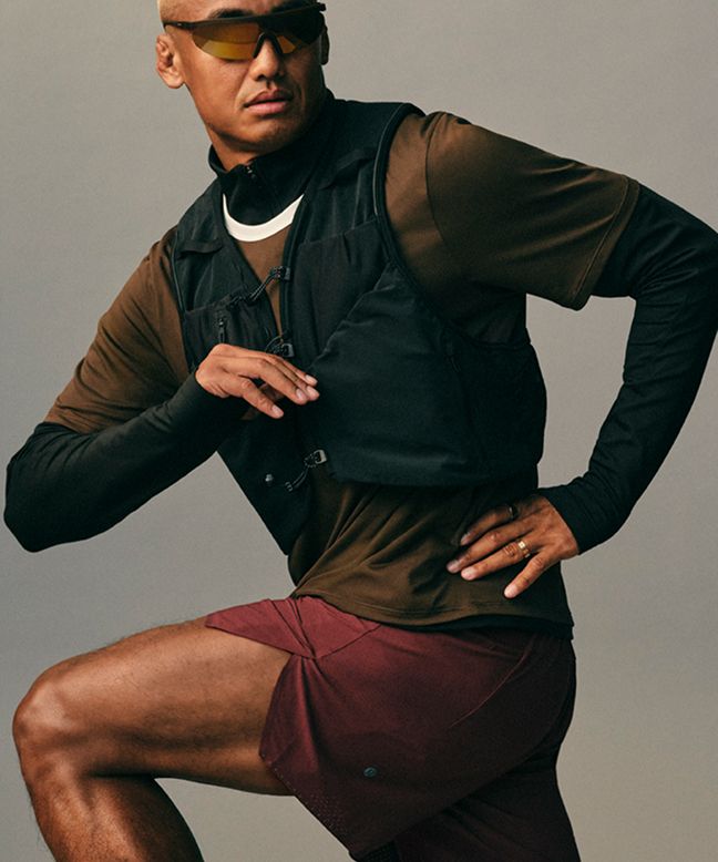 Ein Läufer imitiert Laufbewegung in lululemon Performance-Gear vor einem neutralen Studiohintergrund.