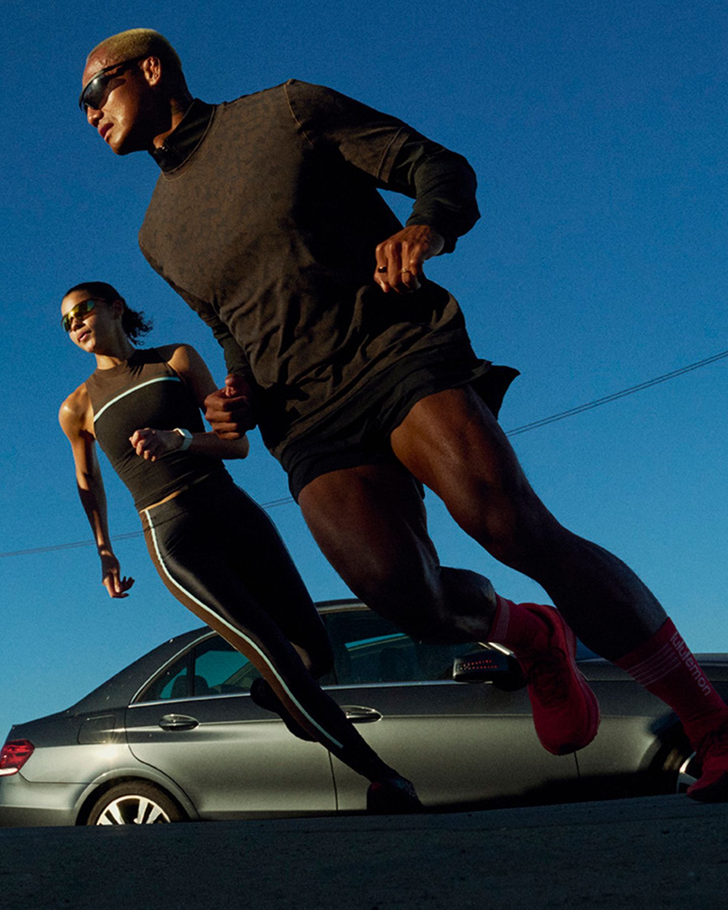 Ein Läufer und eine Läuferin in lululemon Kleidung joggen gemeinsam eine Stadtstraße hinauf.