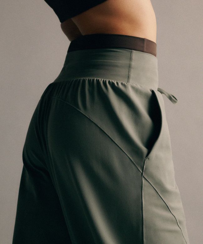 Eine Person beim Yoga, die die Groove Hose mit niedrigem Bund und Kordelzug im Relaxed Fit in der Farbe Willow Leaf trägt.