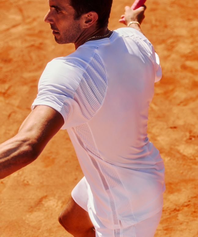 Eine Nahaufnahme einer Person, die Tennis spielt und das Tennisshirt mit Mesheinsätzen und Shorts trägt.