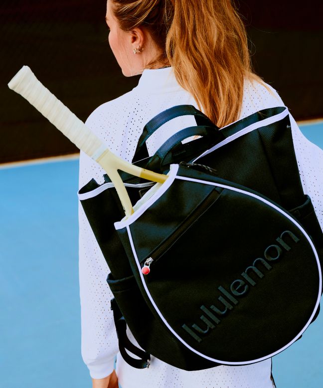 Eine Person trägt die Ace Advantage Tennisjacke aus Strickmaterial und die Schlägertasche.
