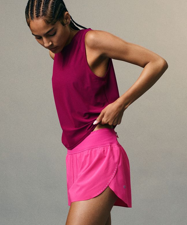 A person wearing a Fast and Free Tank in Raspberry Rave and the Fast and Free Mid-Rise Split Short 3” in Flamingo Fun Tone.
