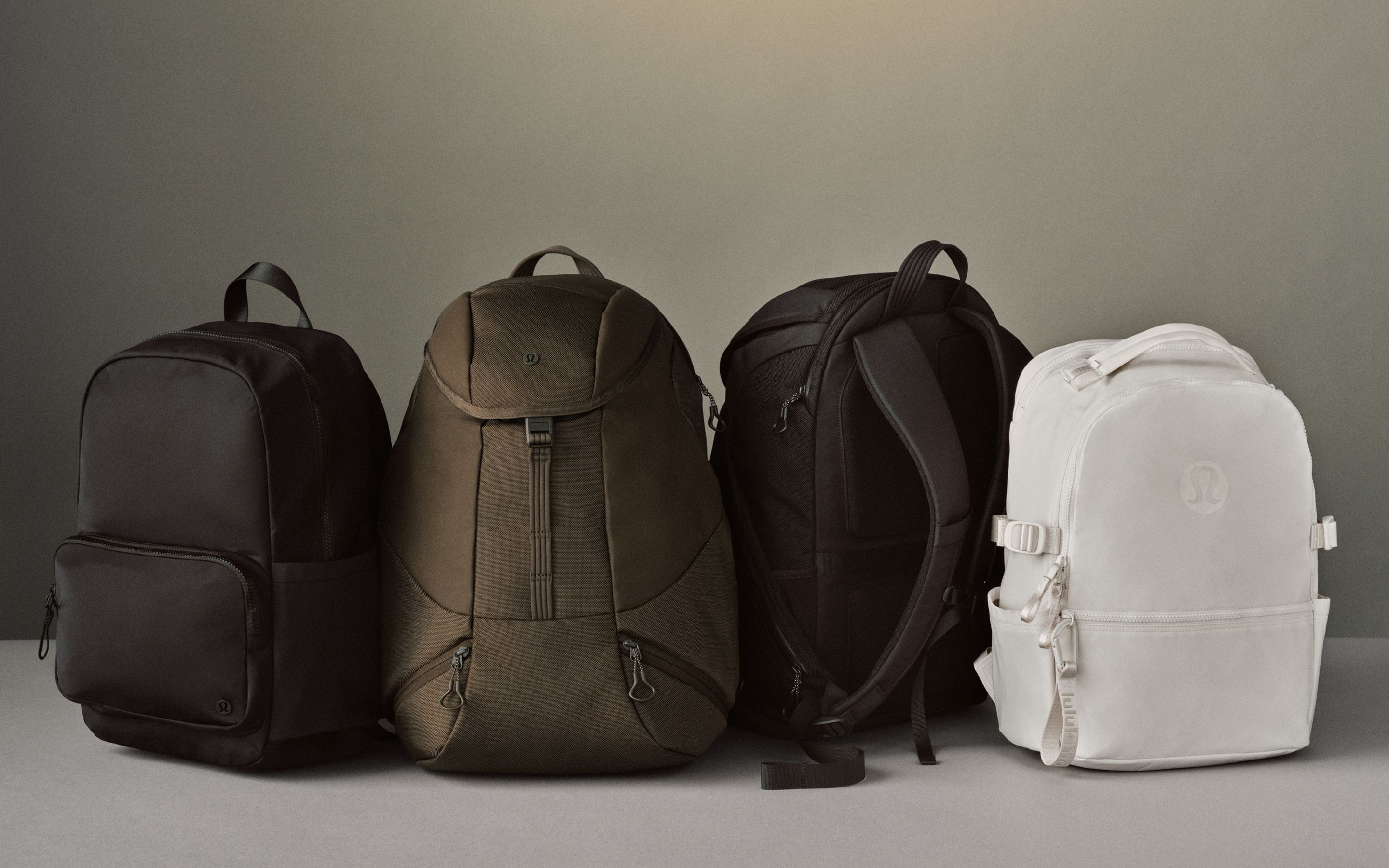 Vier Rucksäcke von lululemon aus verschiedenen Kollektionen vor einem neutralen Hintergrund.