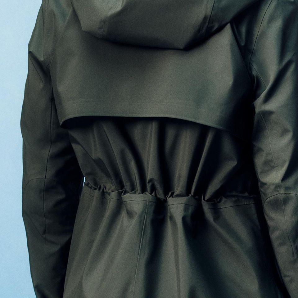 A person wearing the Rain Rebel Waterproof Jacket in Rainforest Green.