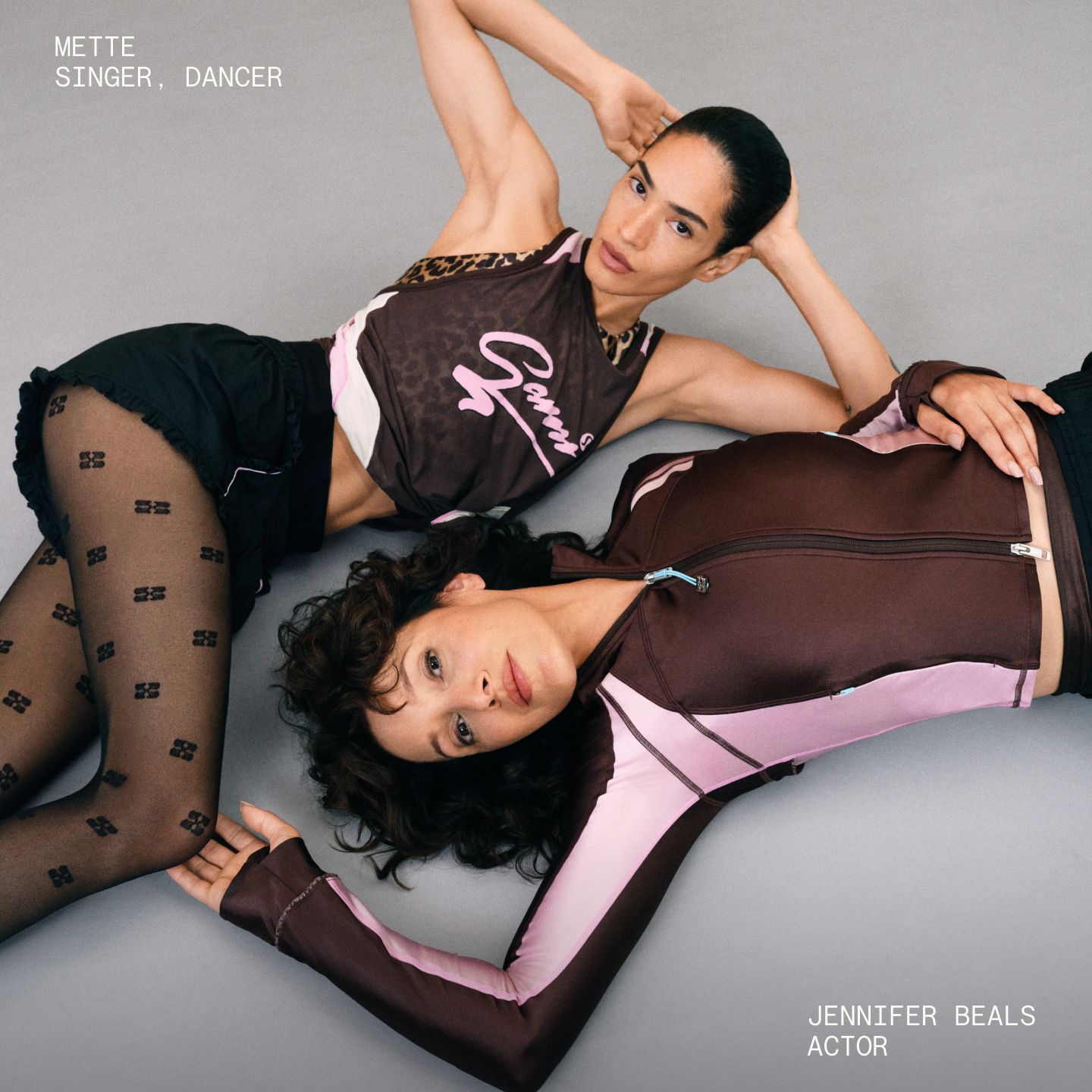 Two people posing on a dance studio floor wearing looks from the collection, including the Jaquard Mesh Tank, Ruffle Trim Textured Short, and Define Ruffle Trim Jacket.