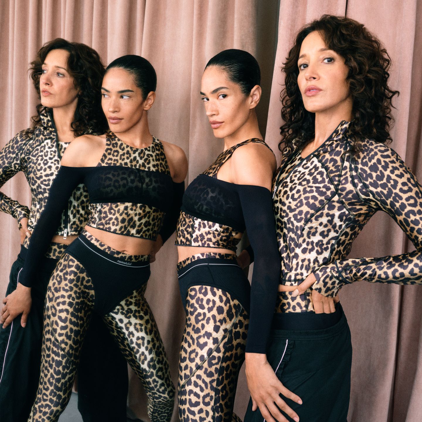 Two people posing in front of a mirror in a dance studio wearing leopard print looks from the GANNI x lululemon collection.