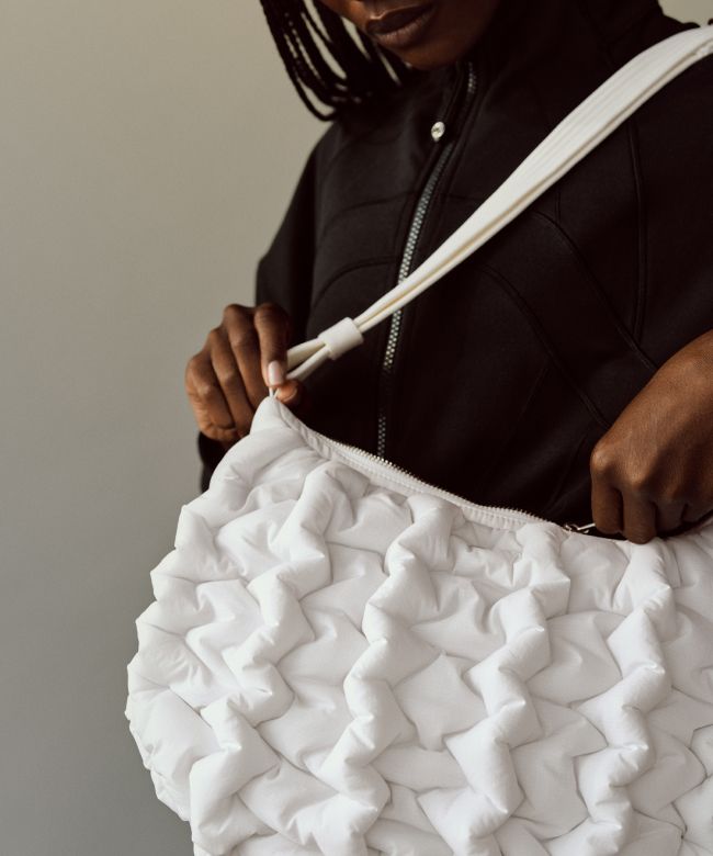A close-up of a person zipping the Quality Puff Crossbody they're wearing on their shoulder.
