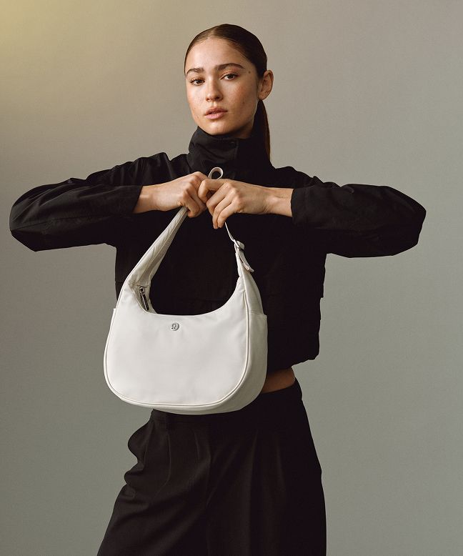 A person is standing and holding up the City Essentials bag.