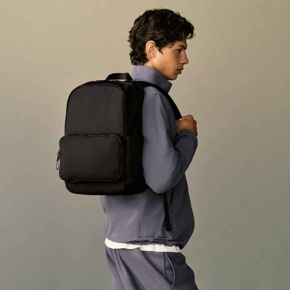 A person stands with a backpack on their back.