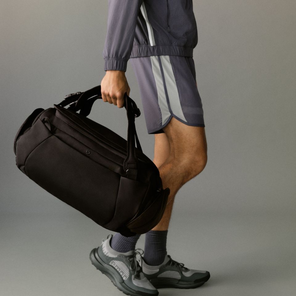 A close-up shot of a person holding a Duffle Bag in their right hand.