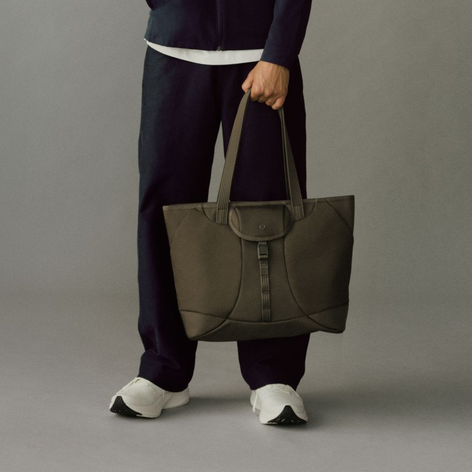 A close-up of someone holding the Daily Dispatch Tote in their left hand.