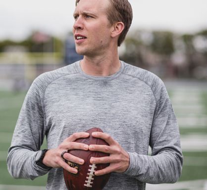 Man posing and looking into the distance while holding a football