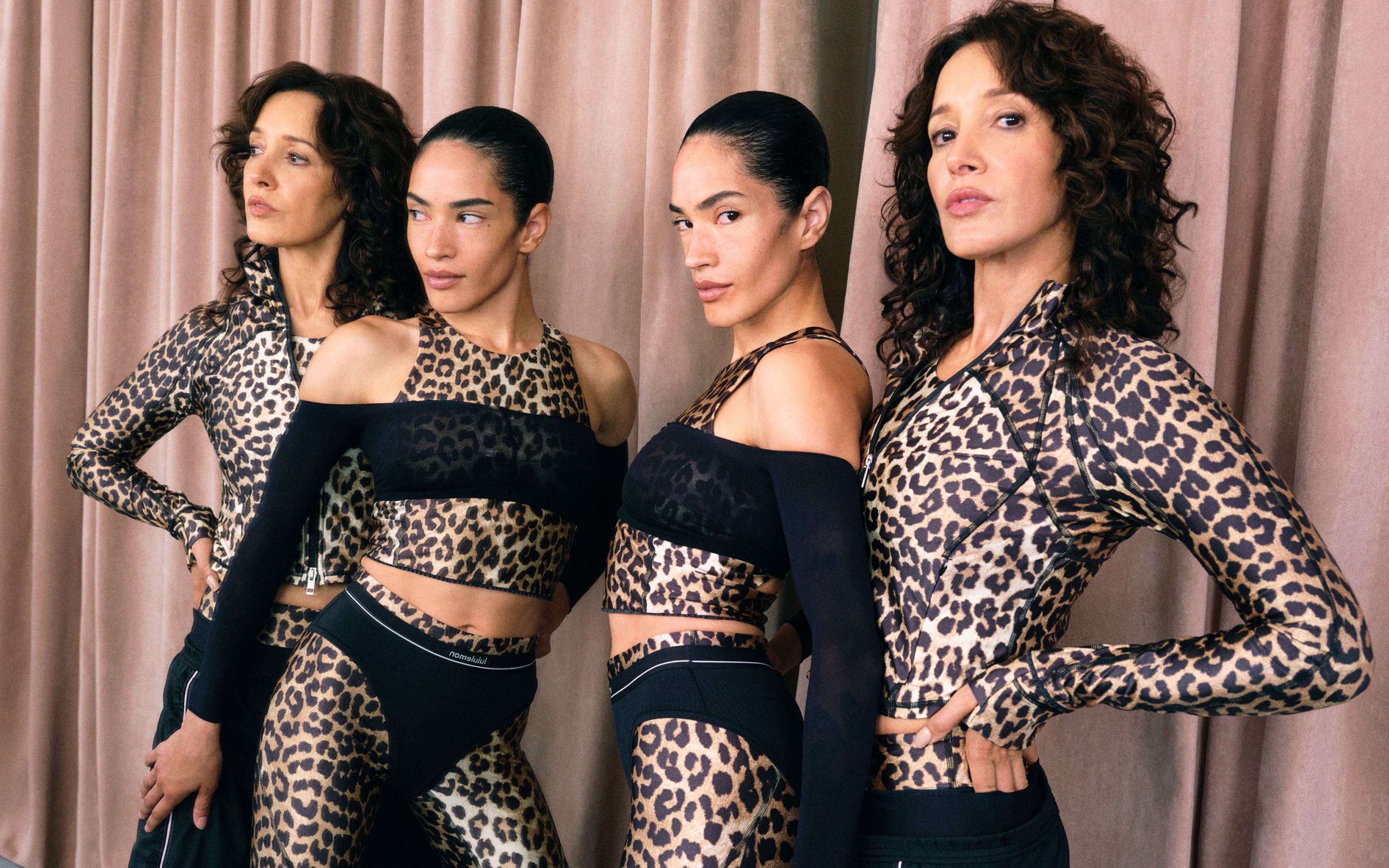Two people posing in front of a mirror in a dance studio wearing leopard print looks from the collection