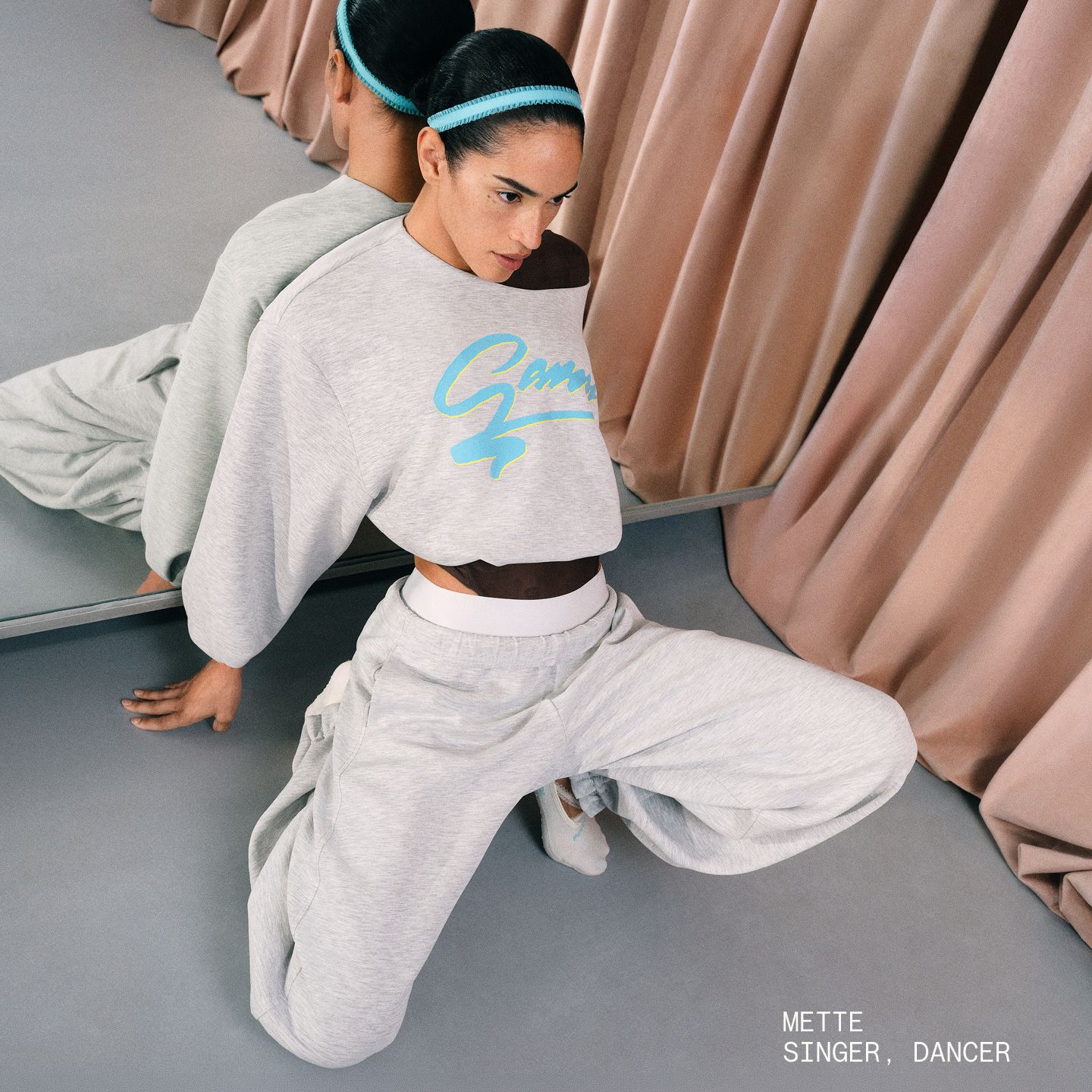 A person leaning on a mirror posing while wearing a matching set featuring an oversize sweatshirt and pants from the collection
