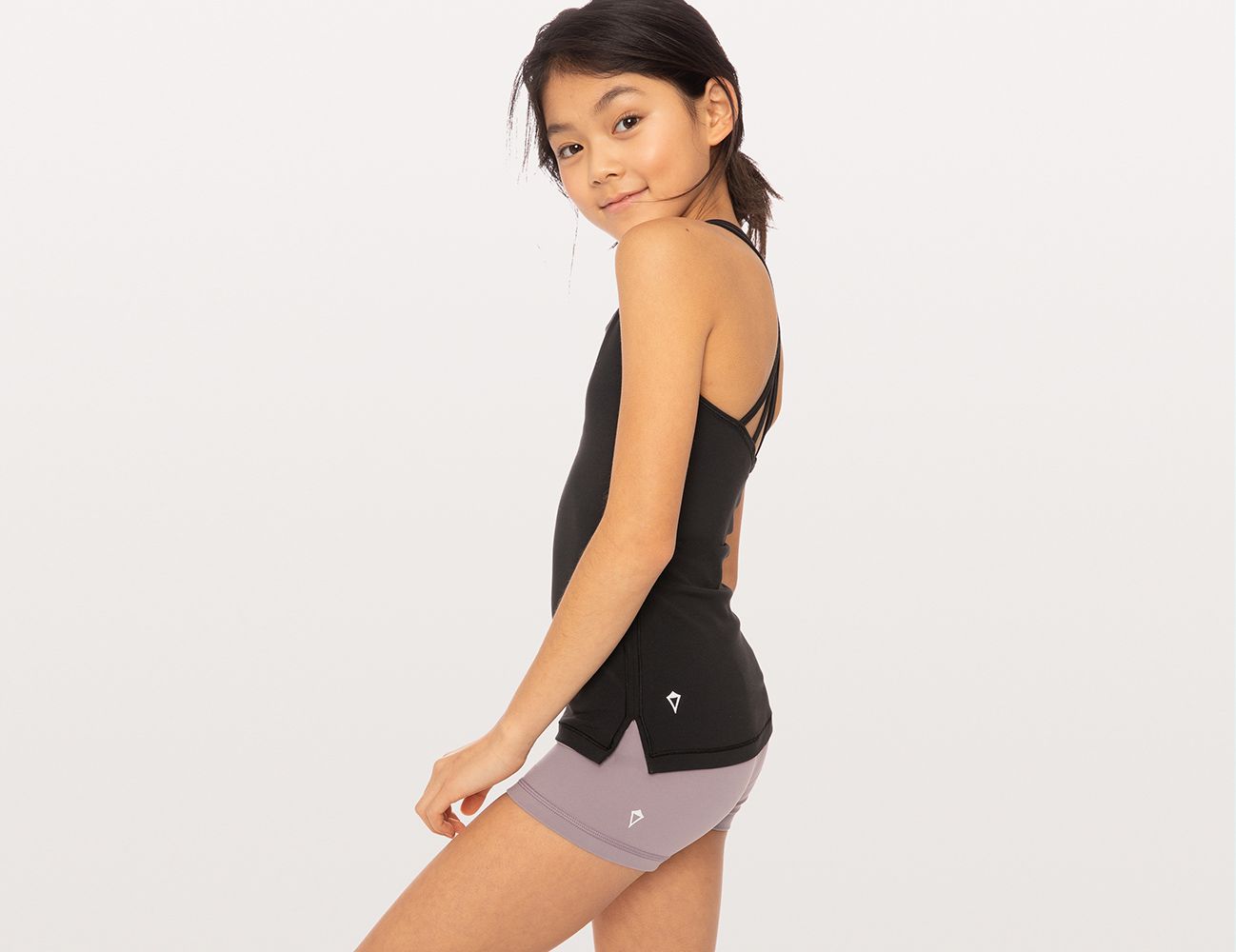 Girl wears black tank and purple shorts. 