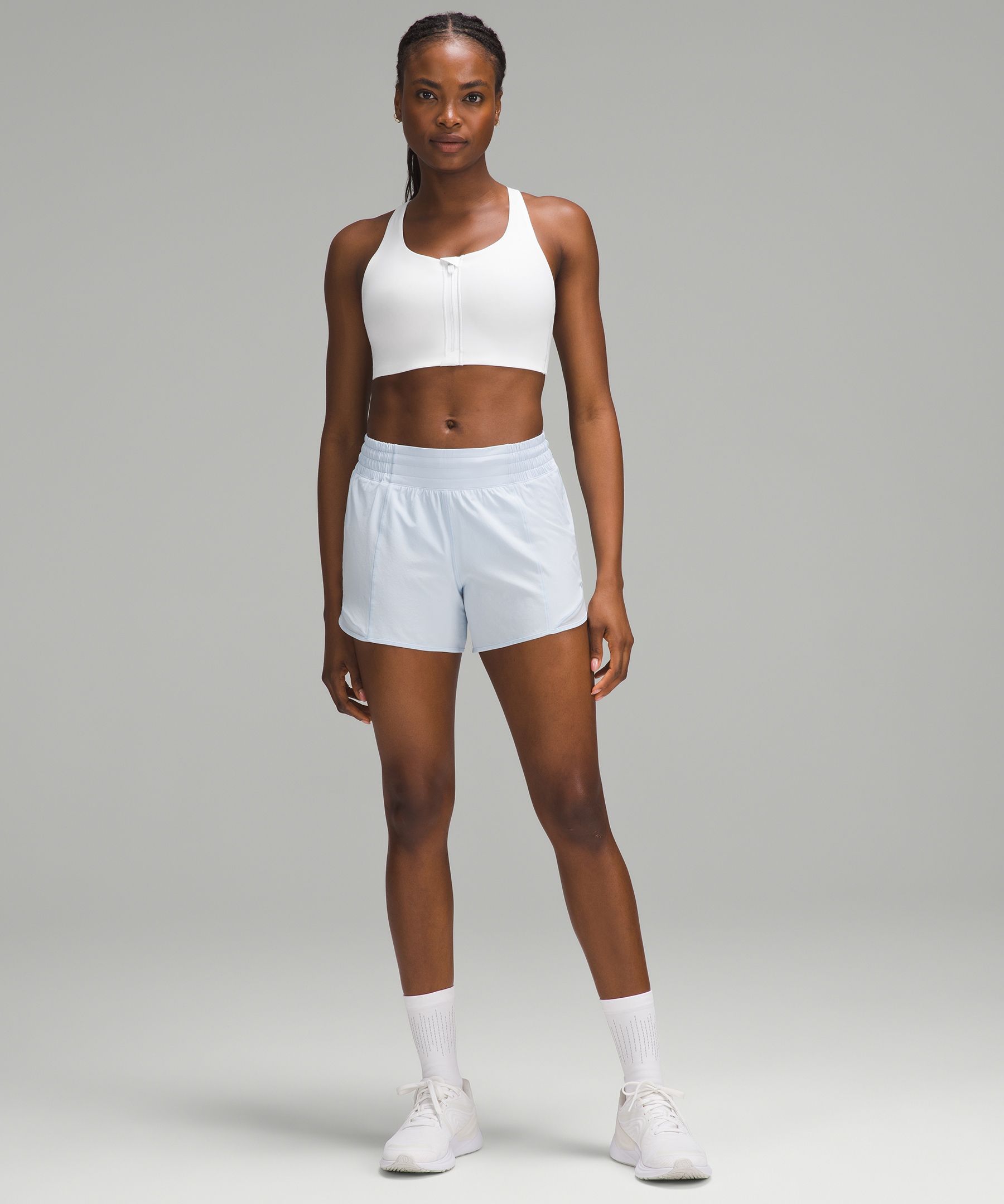 Woman in white sports bra and white shorts holding black and white