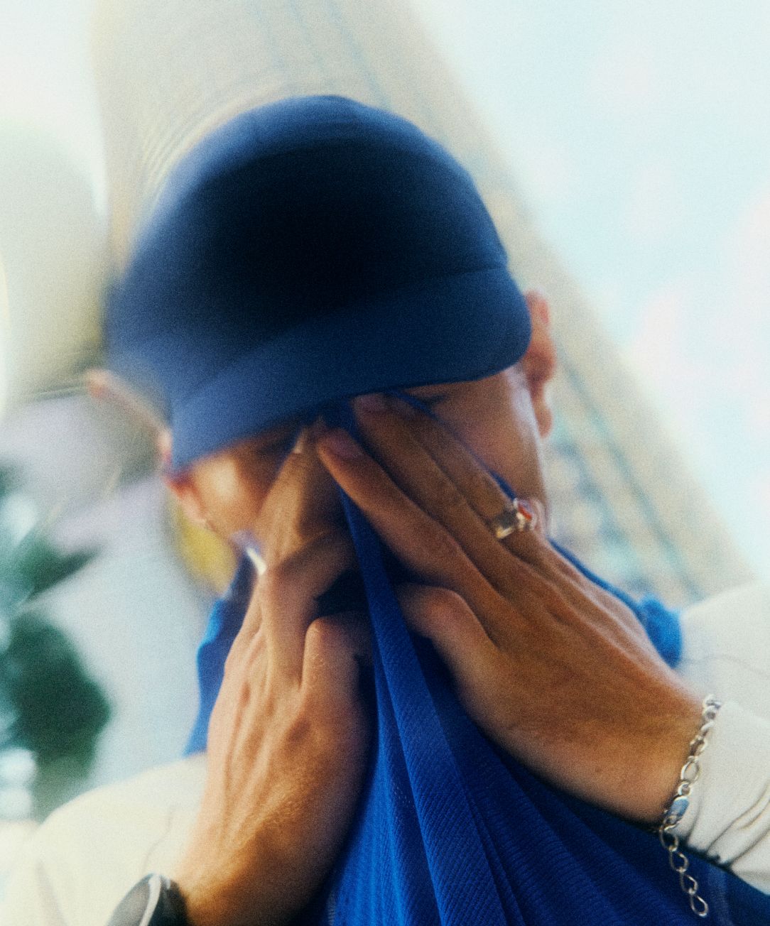 Une personne qui essuie la sueur sur son visage porte la casquette de course et le haut manches courtes Fast and Free Era de lululemon.