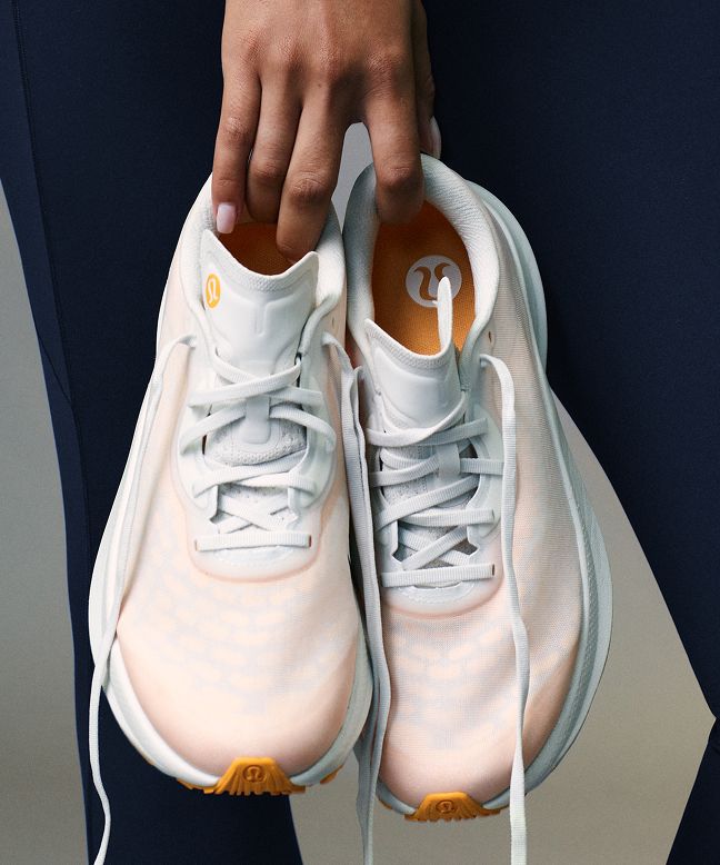 A close-up of a person holding the Split Shift shoes in their hand.
