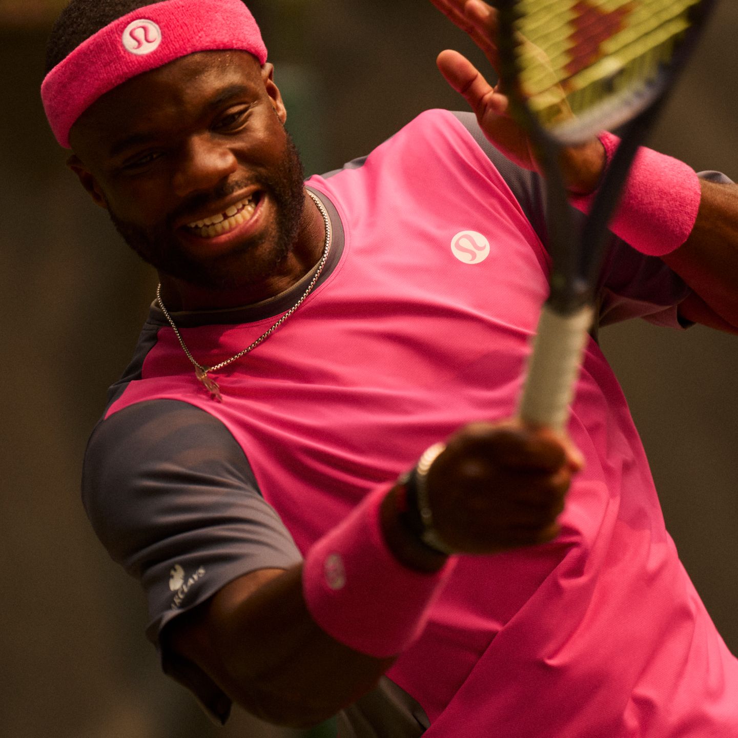 Pro Tennis Player and lululemon Ambassador Frances Tiafoe wears the new Mesh Pique Tennis Short-Sleeve Shirt while hitting a groundstroke. 