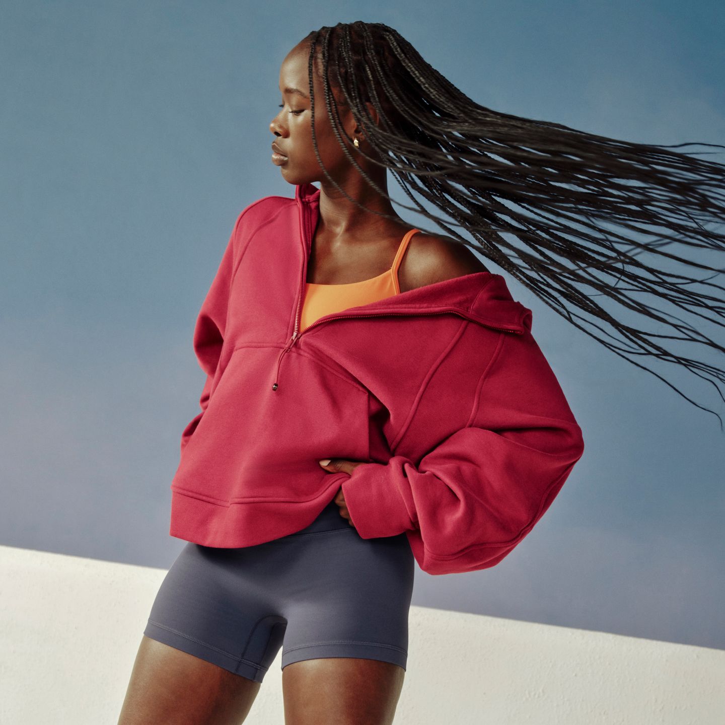 An image of a person facing sideways while their hair whips around. They are wearing the new Scuba Evolve Half-Zip Hoodie and Align No Line Short.