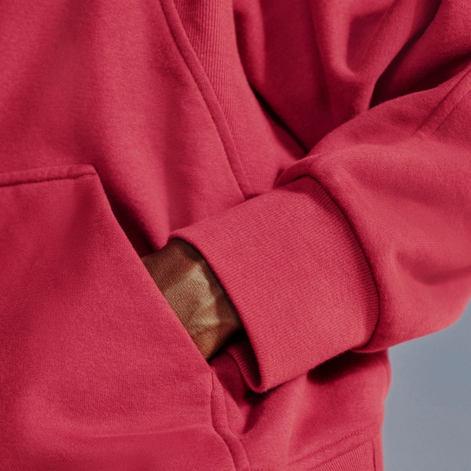 A close-up of a person's hand in the kangaroo pocket on the new Scuba Evolve Half-Zip Hoodie in Raspberry Rave.