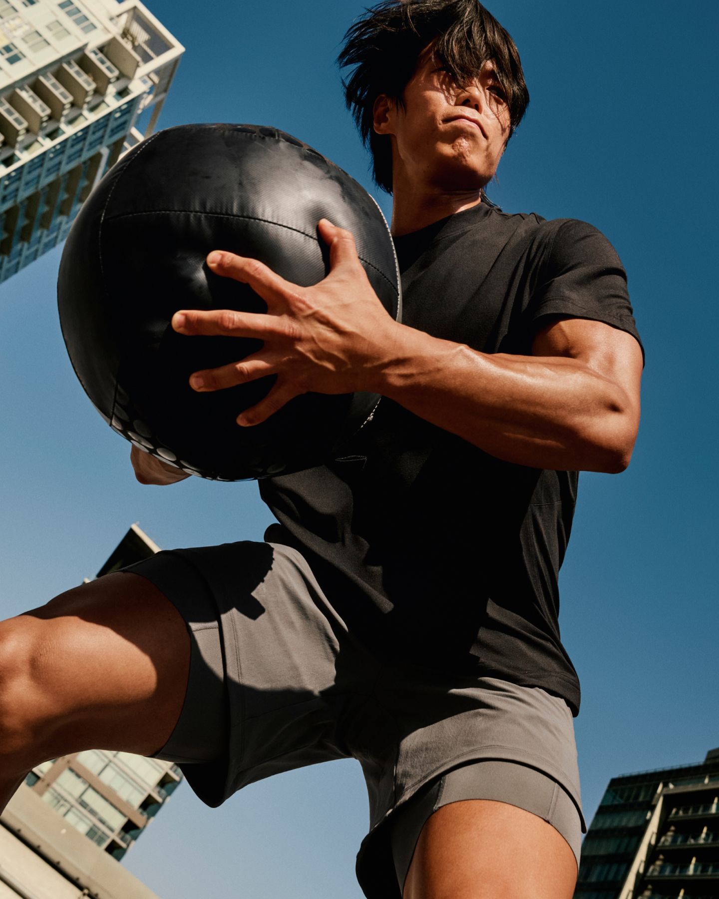 Fitness athlete and lululemon Ambassador Amotti swings a medicine ball outside wearing the EasySet Short-Sleeve Shirt and Unrestricted Power™ Short. 