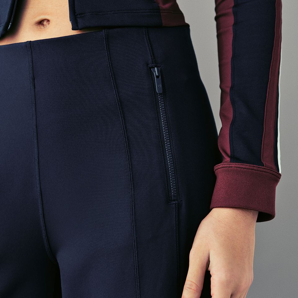 A person wears the Define High-Rise Wide-Leg Pant and Striped Slim-Fit Track Jacket. 