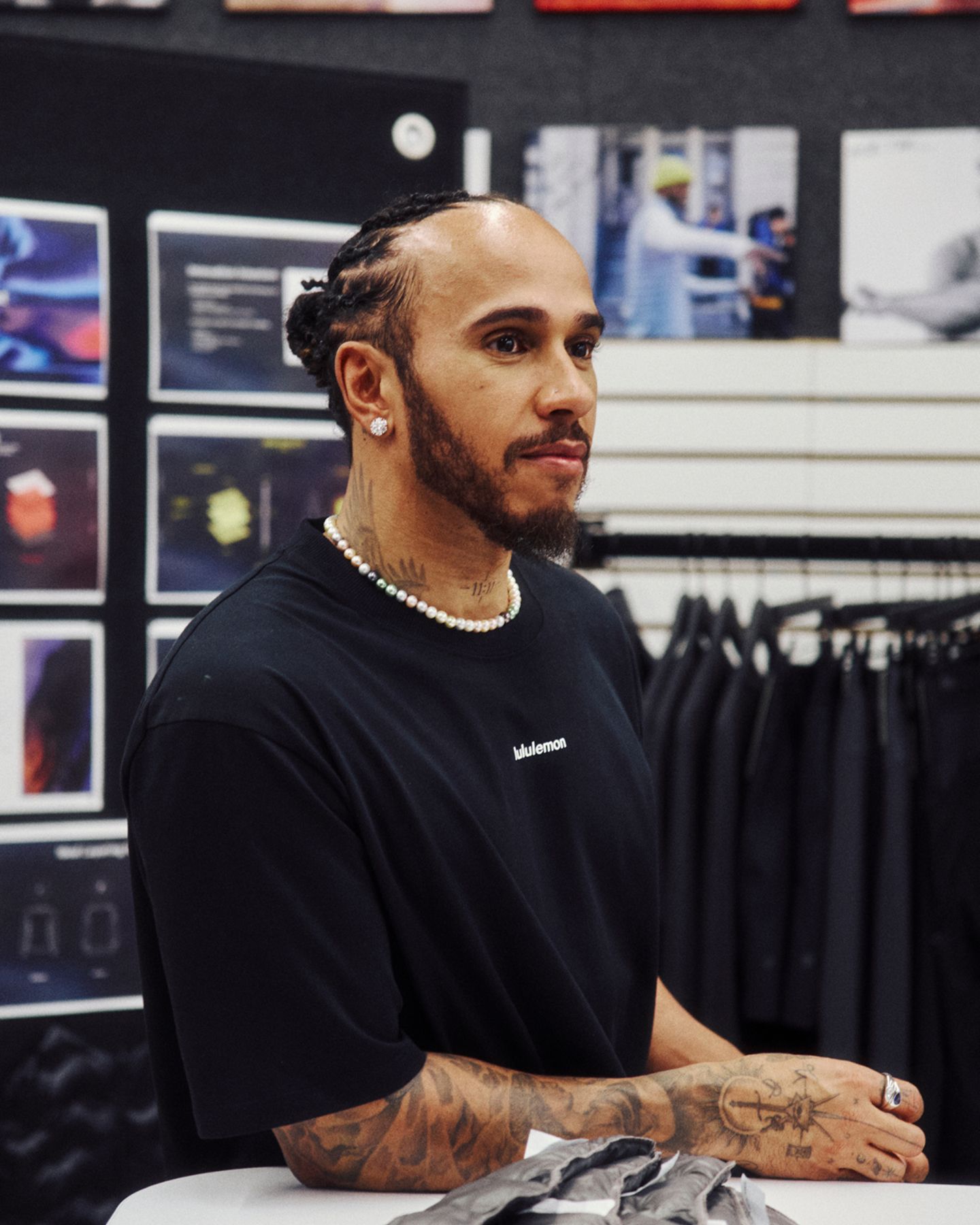 Lewis Hamilton stands at a table in lululemon HQ.