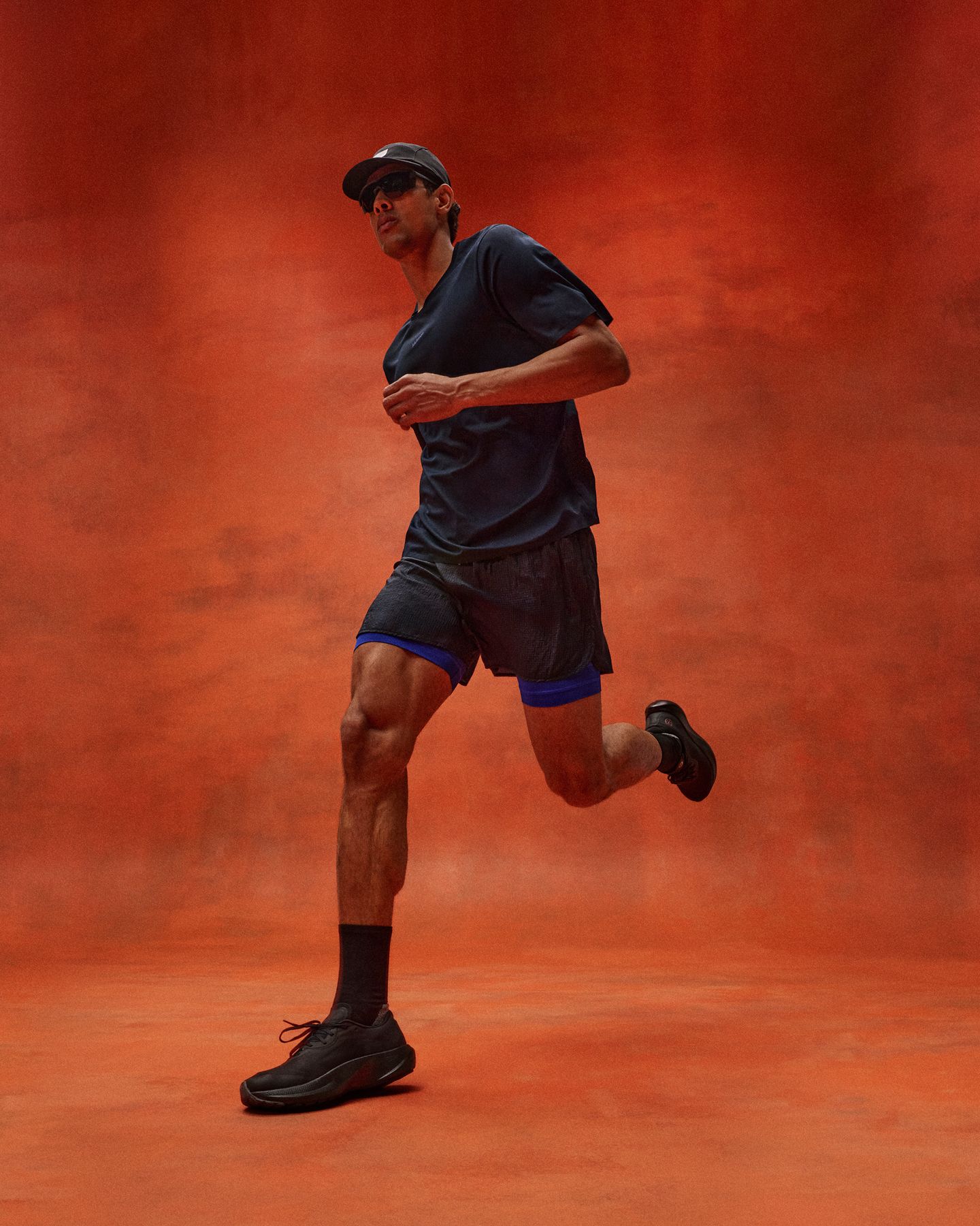 Une personne court en portant de nouveaux vêtements de course pour hommes lululemon, dont le chandail manches courtes Fast and Free et le short Ultralight en Ripstop, devant un fond rouge.