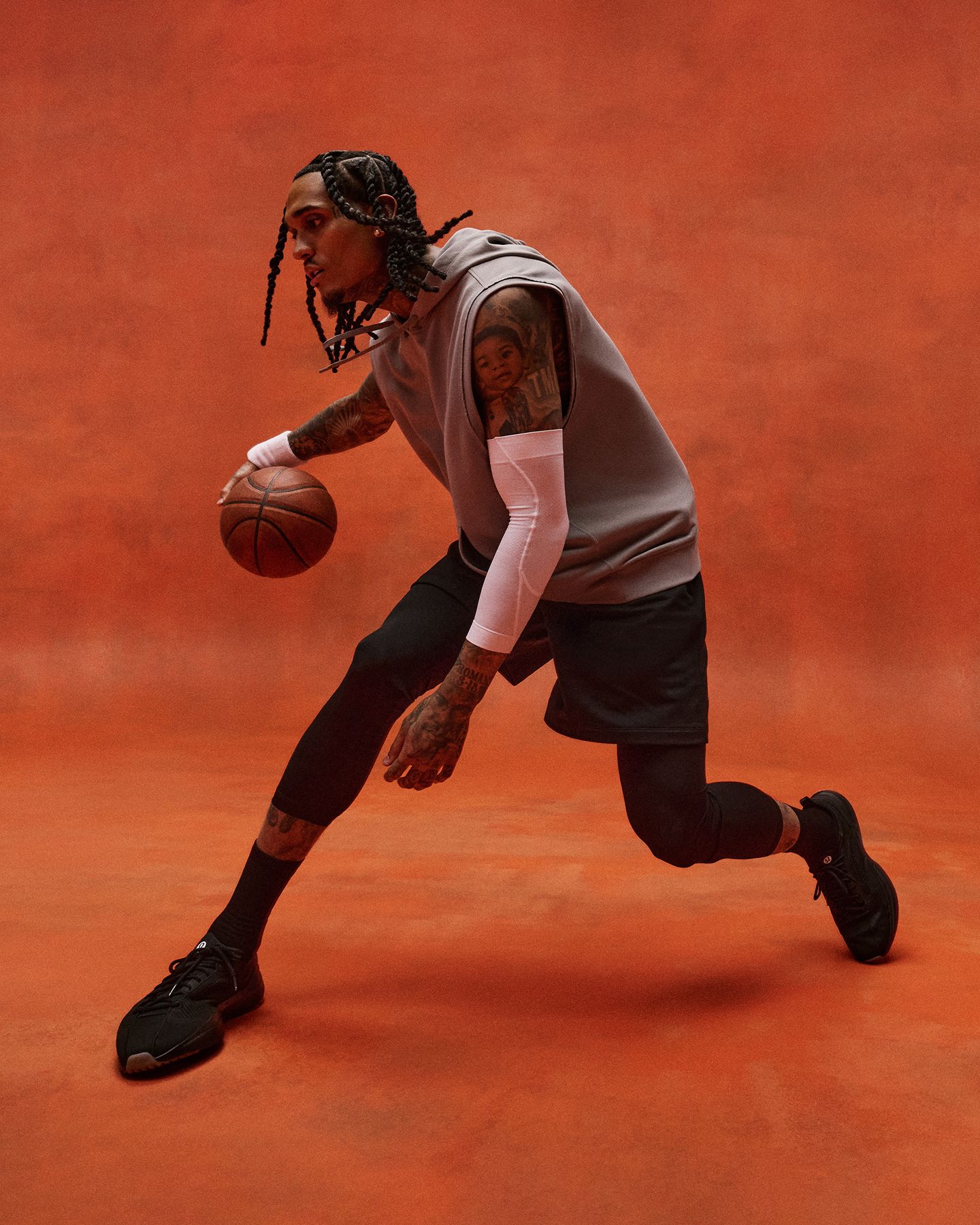 L’ambassadeur et joueur de basketball professionnel Jordan Clarkson fait rebondir un ballon de basketball devant un fond rouge. Jordan porte des vêtements d’entraînement lululemon, dont le chandail à capuchon Warm-Up Gym et le short Warm-Up Gym.