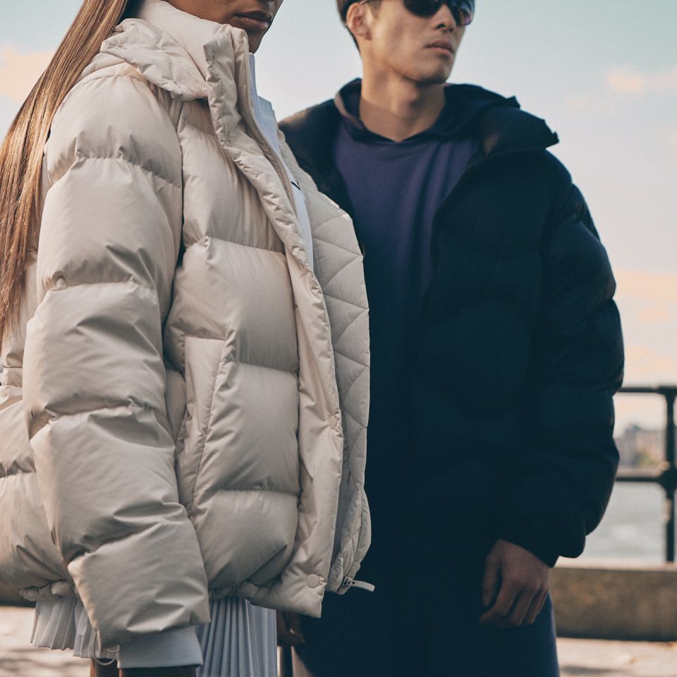 A person wearing a Wunder Puff jacket stands next to a person wearing a Featherweight jacket. 