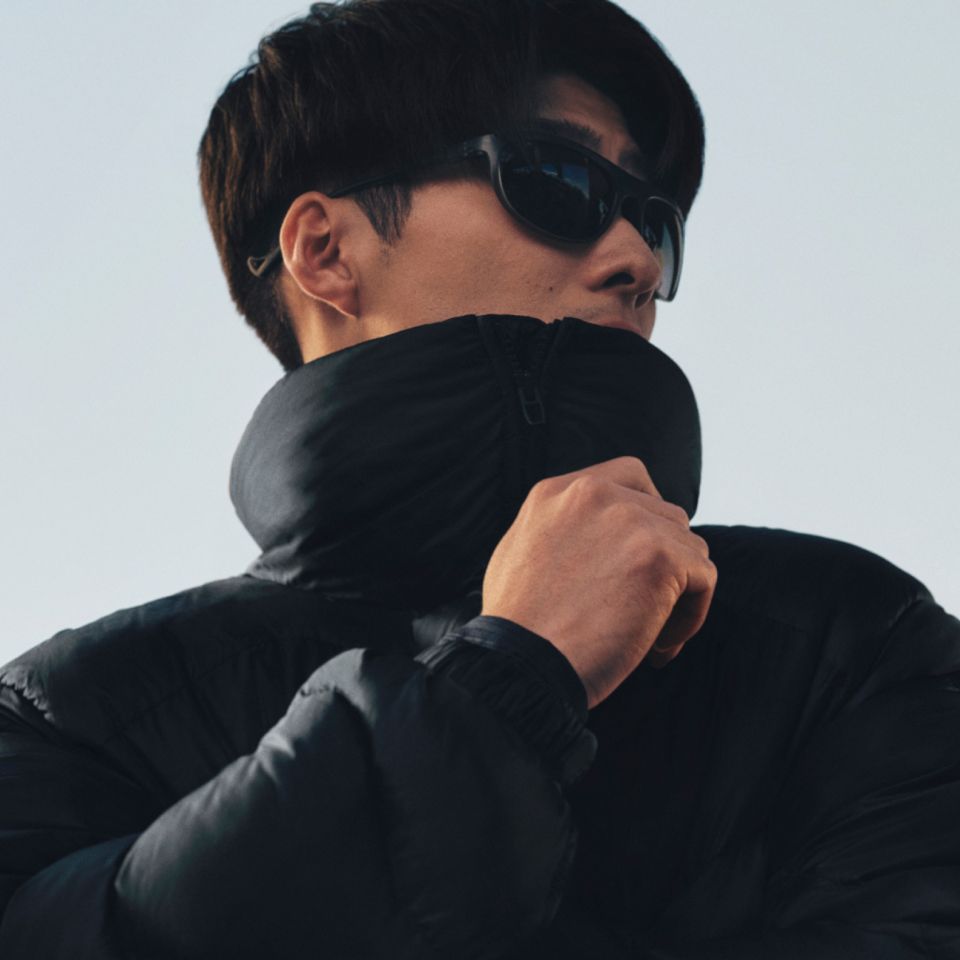 A close-up of a person zipping up the stand collar of a Featherweight jacket. 
