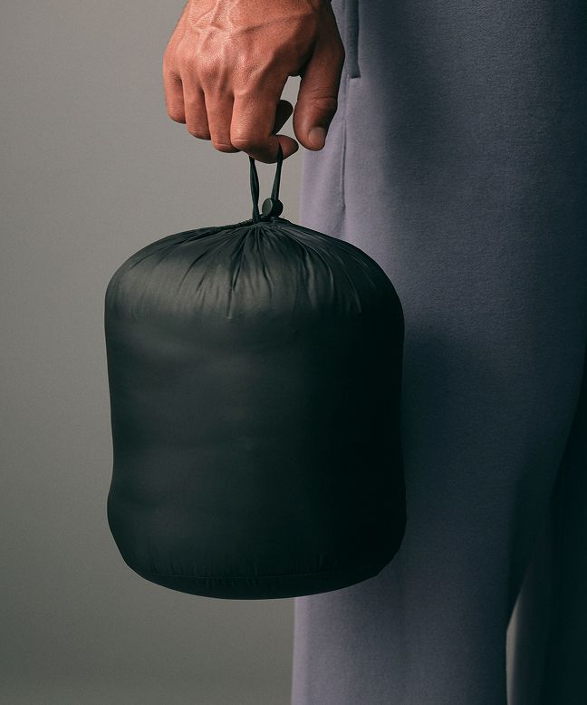 A person holding the removeable stuff sack with a Featherweight jacket stashed inside. 