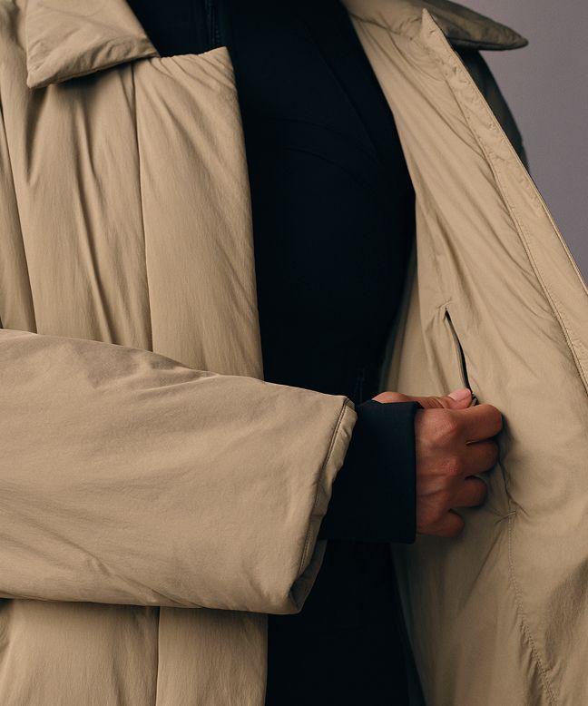 A close-up of a person opening the ThermoZen jacket to reveal an inner zip pocket. 