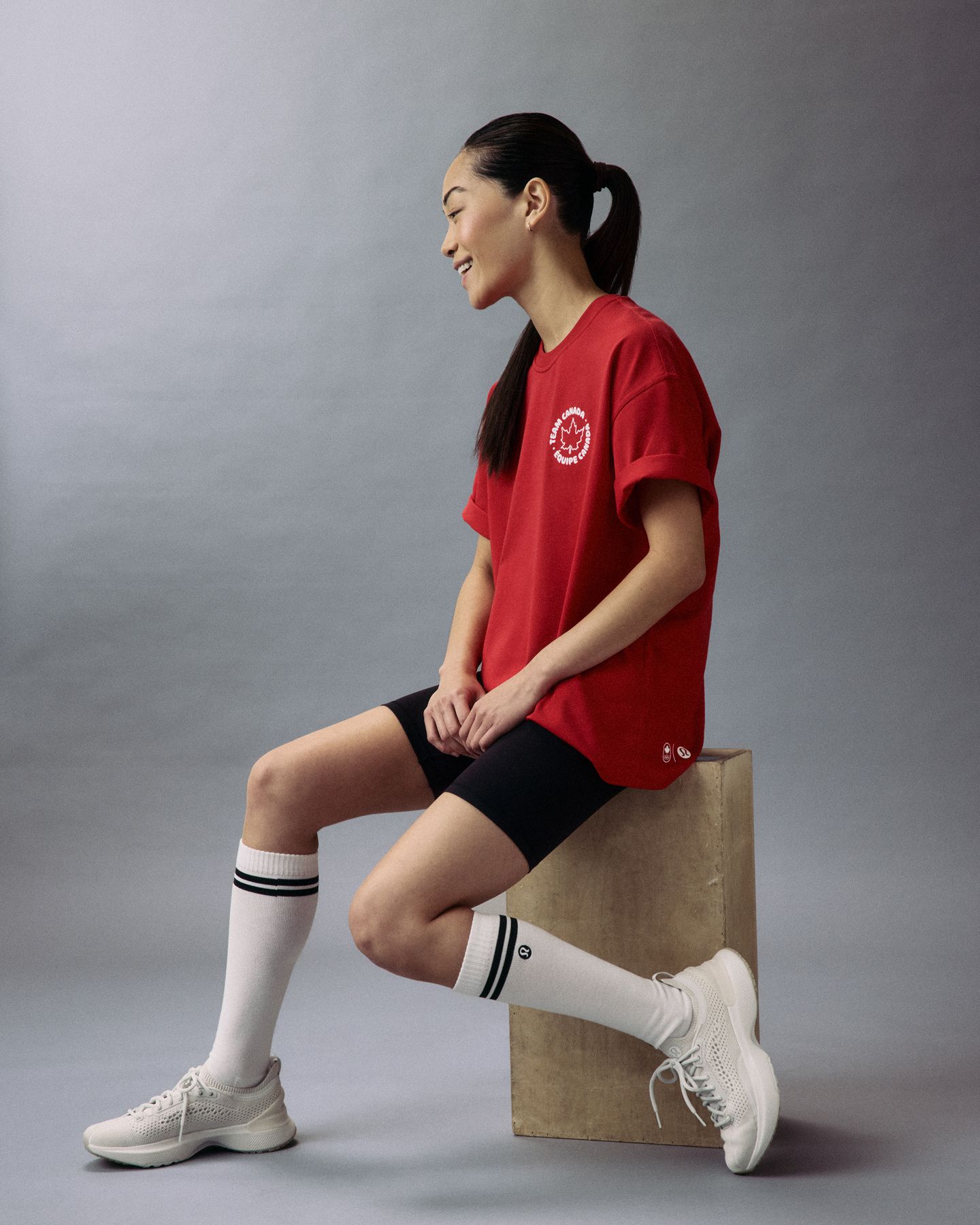 An athlete sits on a wood box wearing the Team Canada Cotton Jersey Short Sleeve T-shirt. 