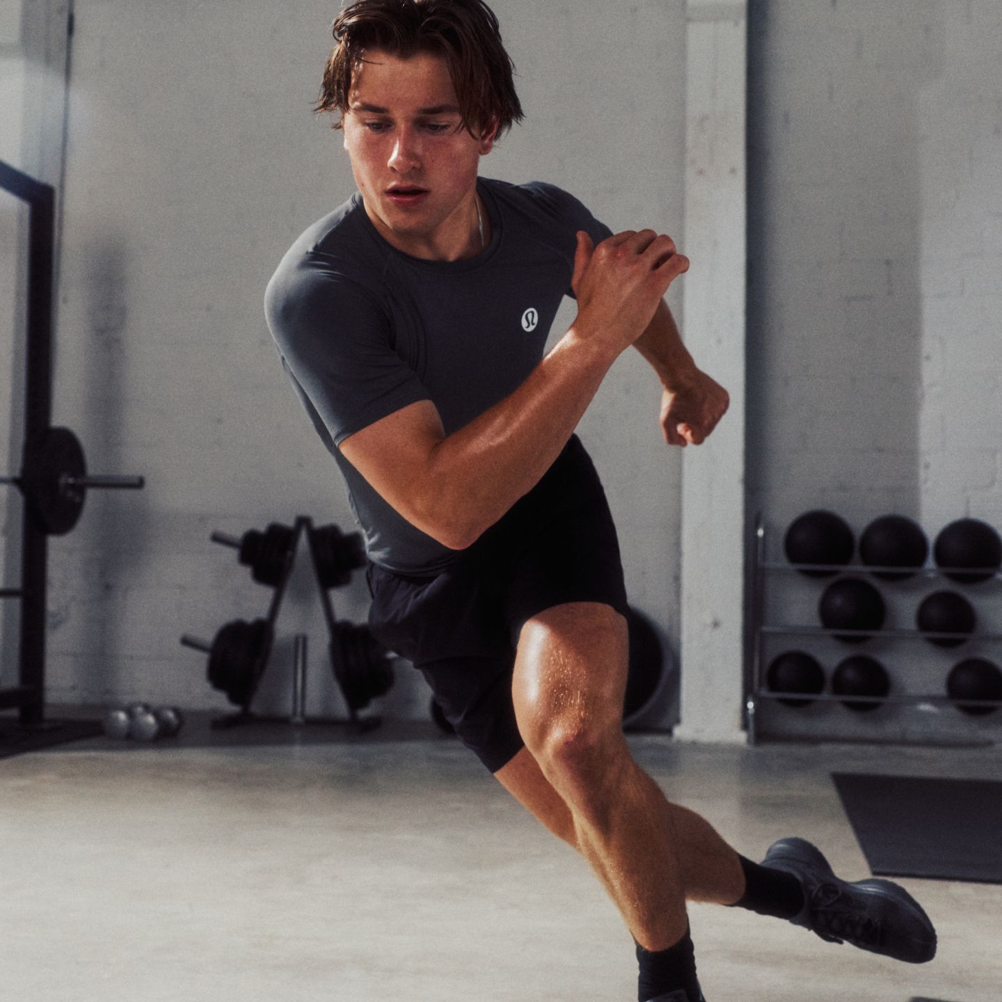 Professional Ice Hockey Player and lululemon Ambassador Macklin Celebrini does skater jumps in a gym while wearing the Unrestricted Power Shirt and the Pace Breaker Short.