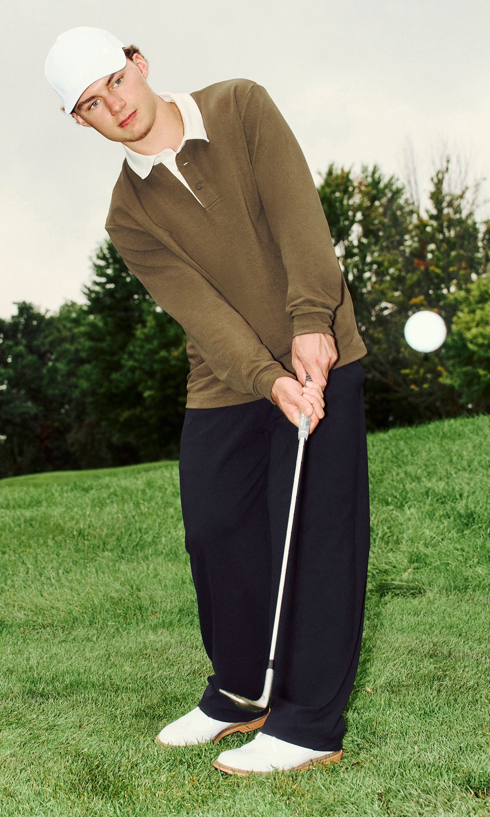 A golfer wears the Daydrift Trouser. They prepare to swing. They tend the flag. They crouch down to read the green. They look ahead after striking the ball.