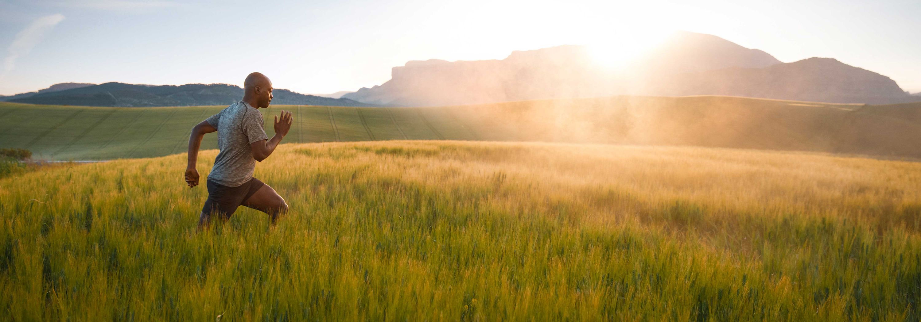 Side view of man running in grassy field.