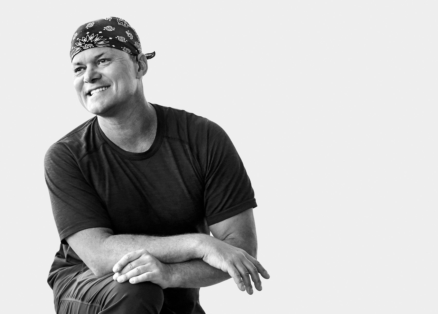 Global Yoga Ambassador Baron Baptiste smiling and resting arms on knee