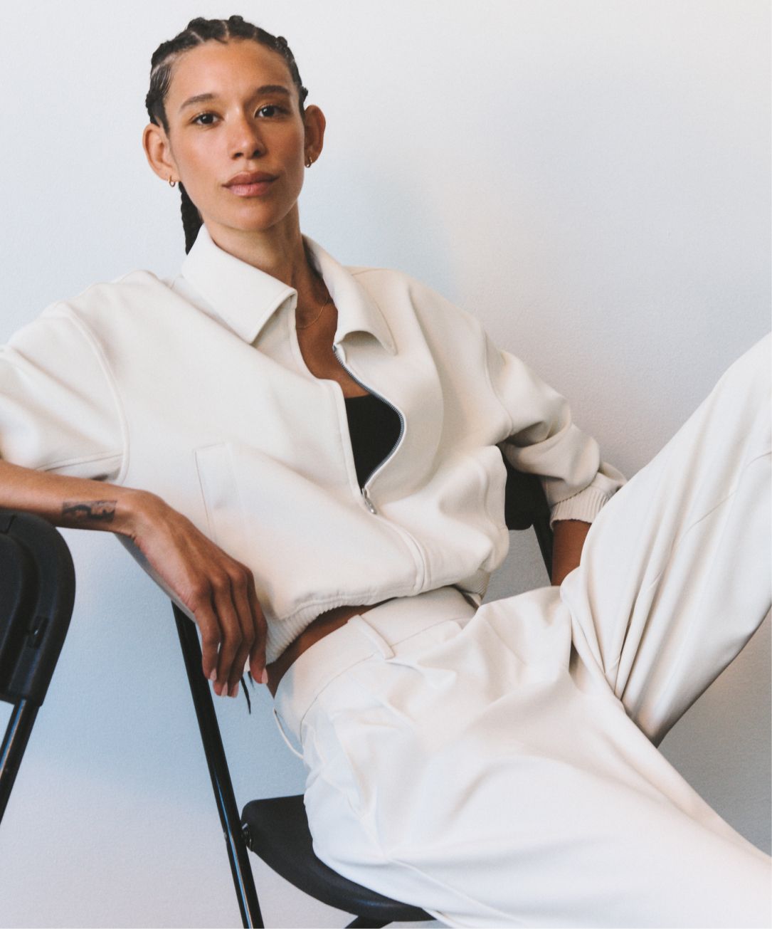 A person wearing a lululemon Daydrift Bomber Jacket and Daydrift High-Rise Wide-Leg Trouser sits on a black leather chair against a neutral background.