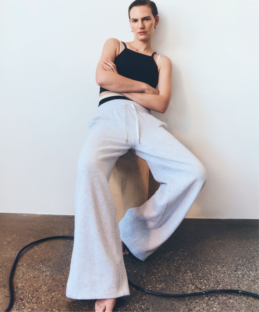 A person leans against a neutral wall while sitting on a wood block. They’re wearing the lululemon Align Layered High-Neck Tank and Scuba Mid-Rise Wide-Leg Pant.