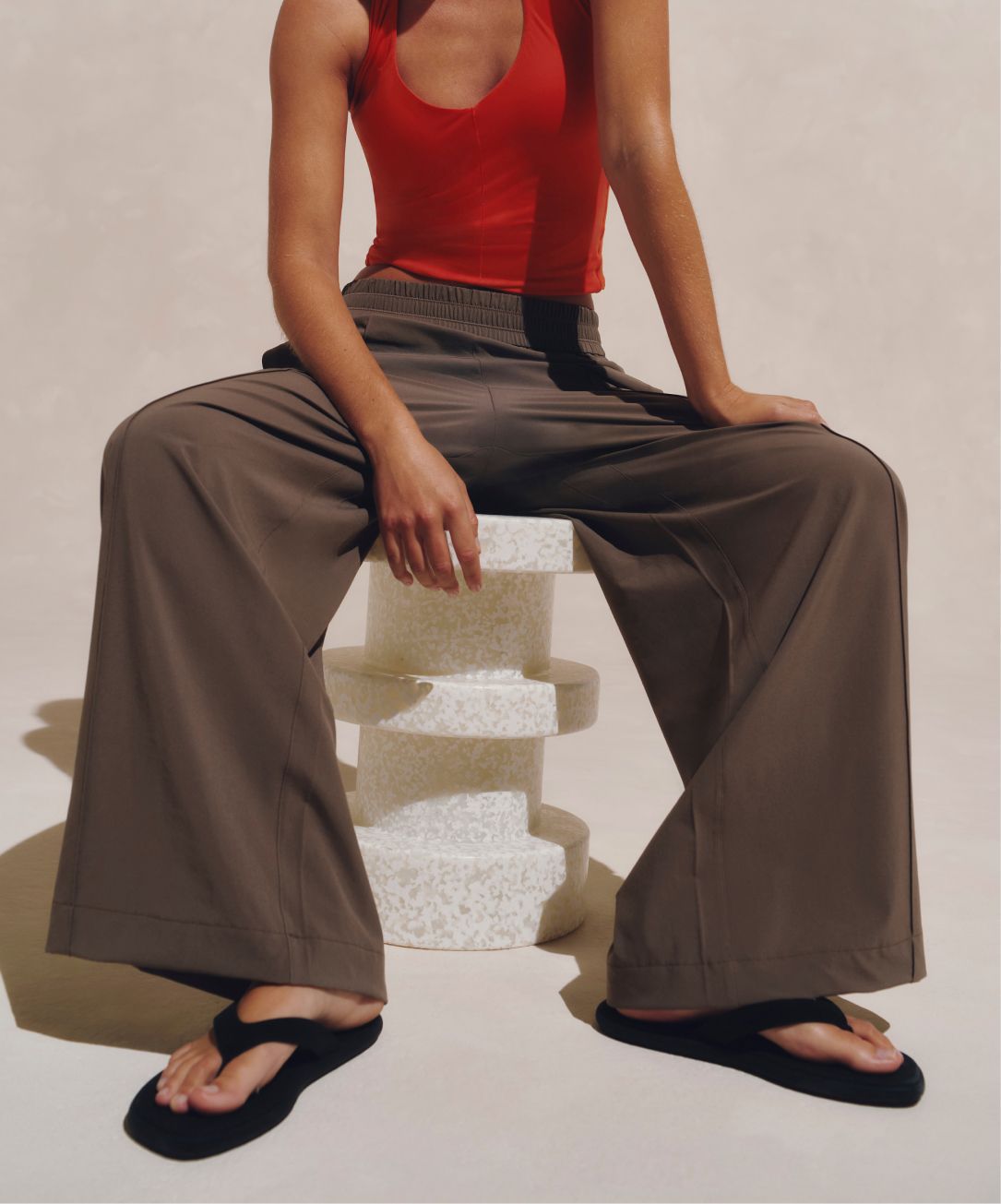 A person poses wearing the Breezily Pants in Nomad and Nulu Halter Tank in Cherry Ember