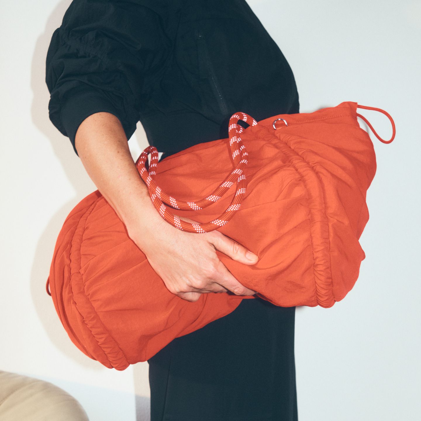 A close-up profile of a person clutching the lululemon Ruched Tote in front of a neutral backdrop. 