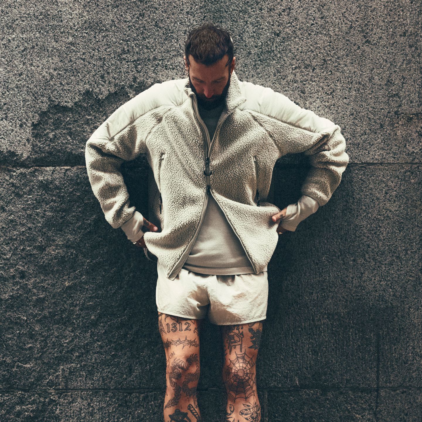 lululemon Ambassador Dennis Roloff looks down with his hands in his pockets. He is outside wearing new styles from the fall 2026 line.   