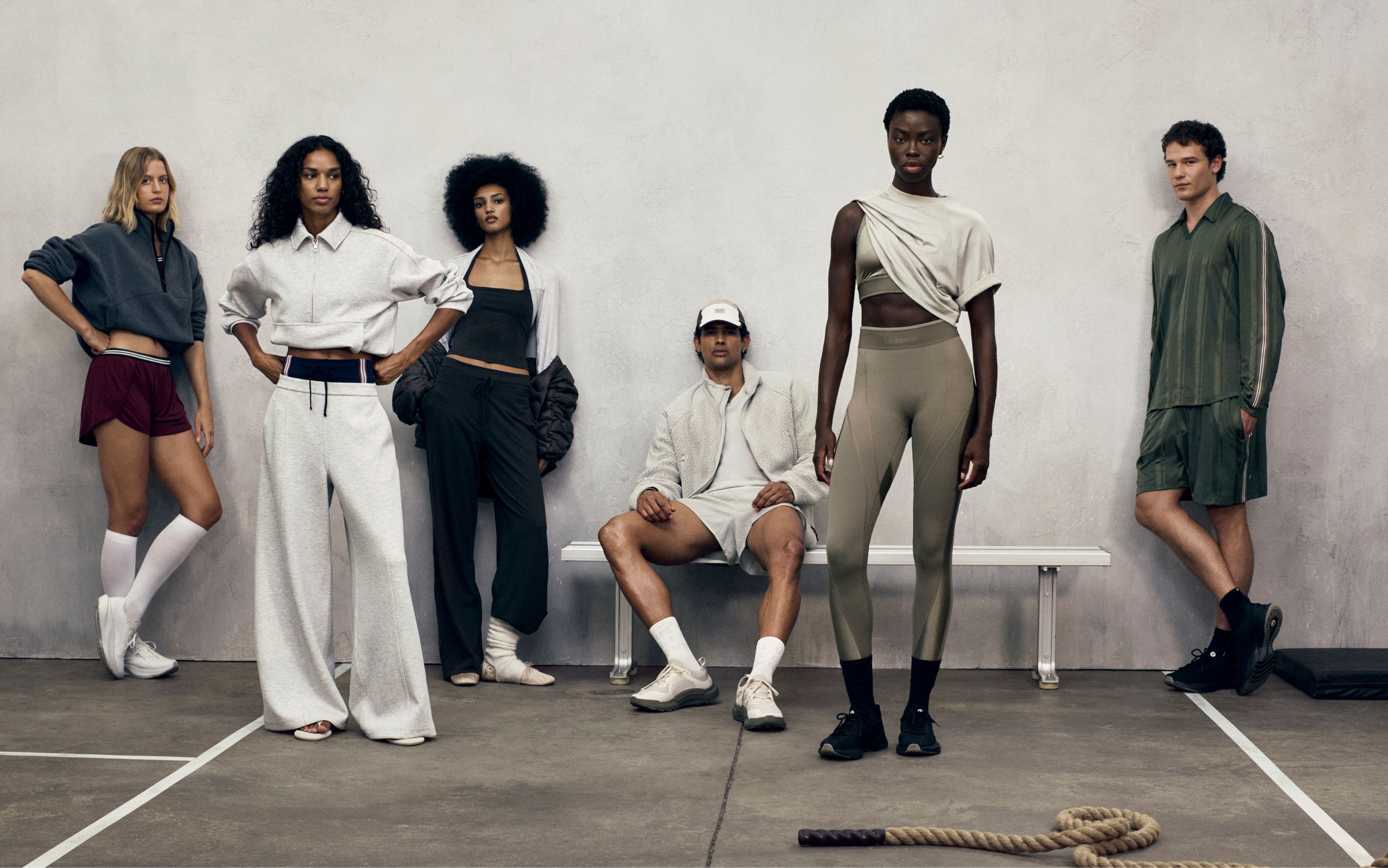 A group of people pose in a line. The person in the middle sits on a bench while the others stand. They are wearing new styles from the fall 2026 line.