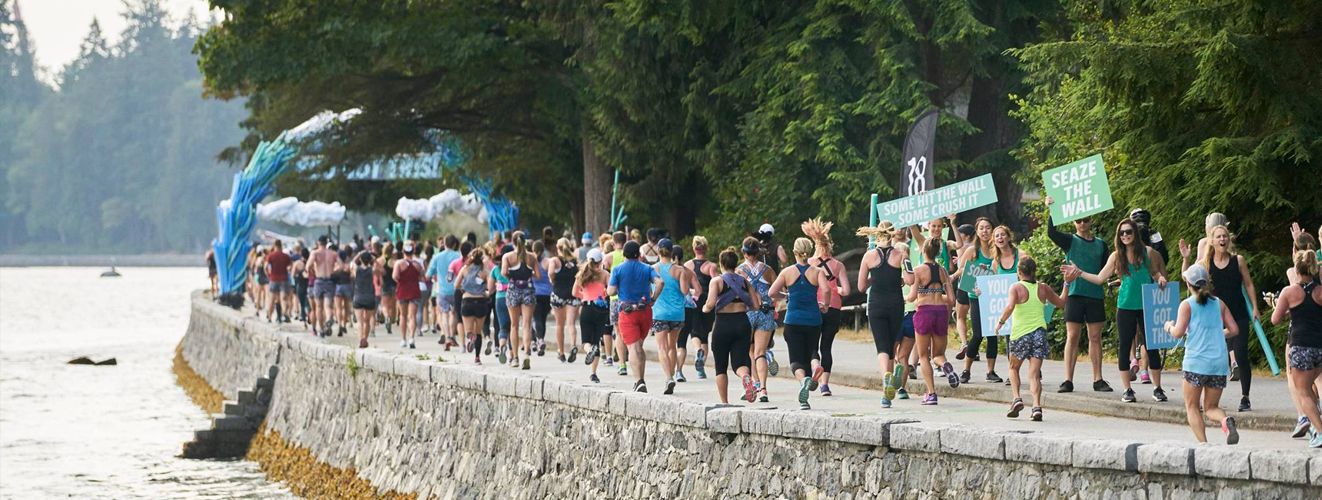 A large crowd of runners running by a body of water.